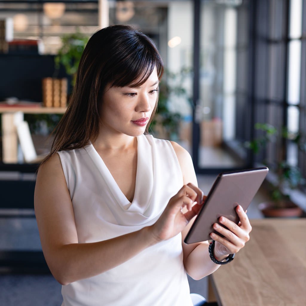 Professional using a tablet while reviewing information in a modern workplace