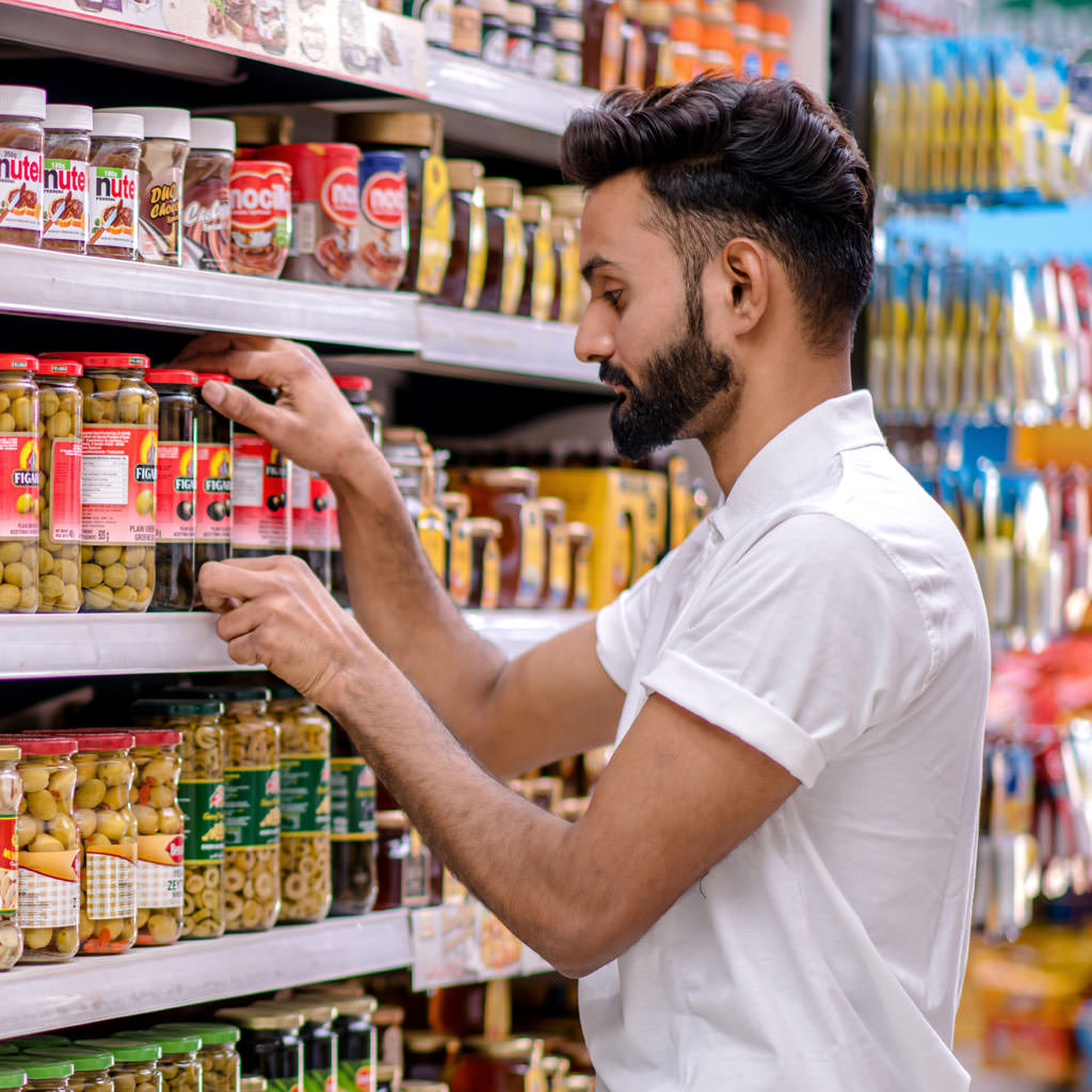 Retail merchandiser restocking products on a supermarket shelf to maintain availability