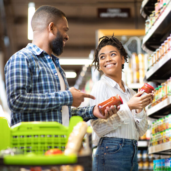 Shoppers comparing products on a supermarket shelf while making a purchase decision
