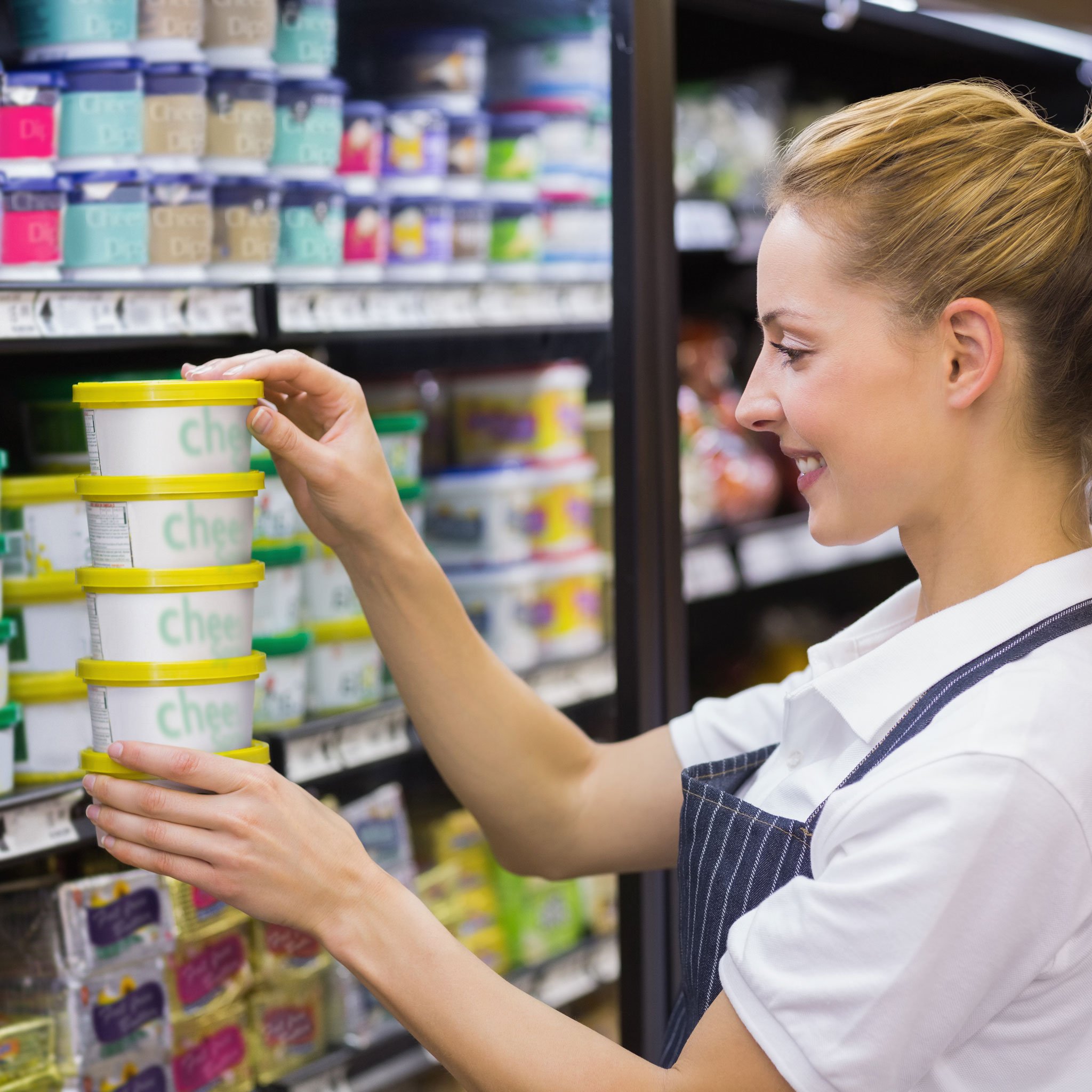 Retail worker arranging dairy products on a supermarket shelf