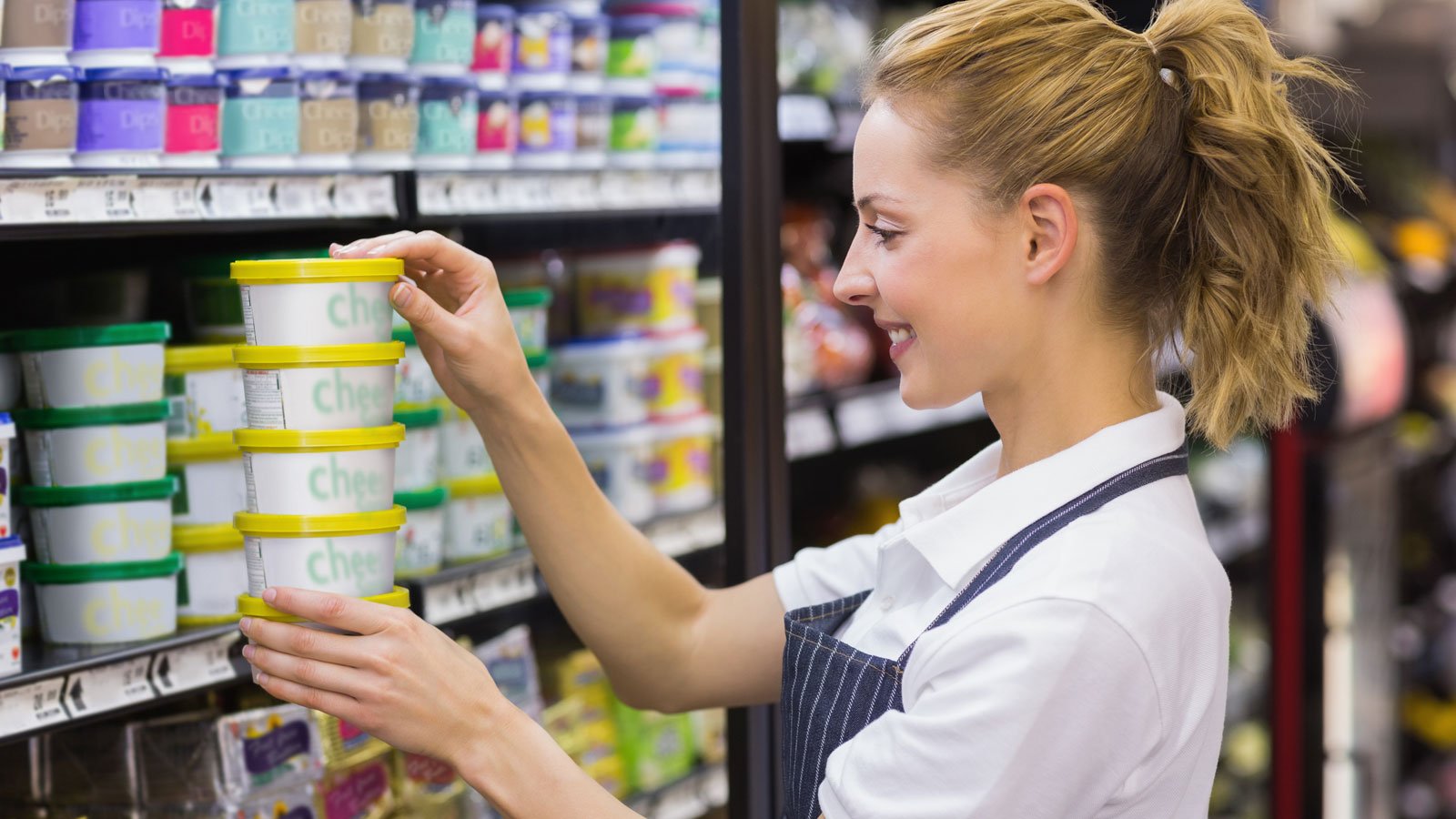 Retail worker arranging dairy products on a supermarket shelf