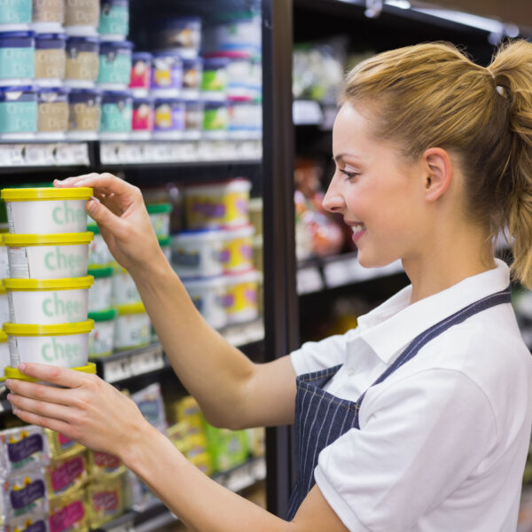 Retail worker arranging dairy products on a supermarket shelf