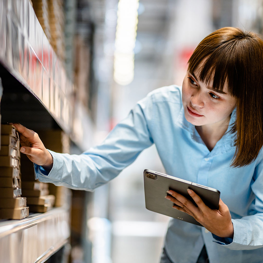 Warehouse worker using a tablet to check inventory and stock levels on warehouse shelves