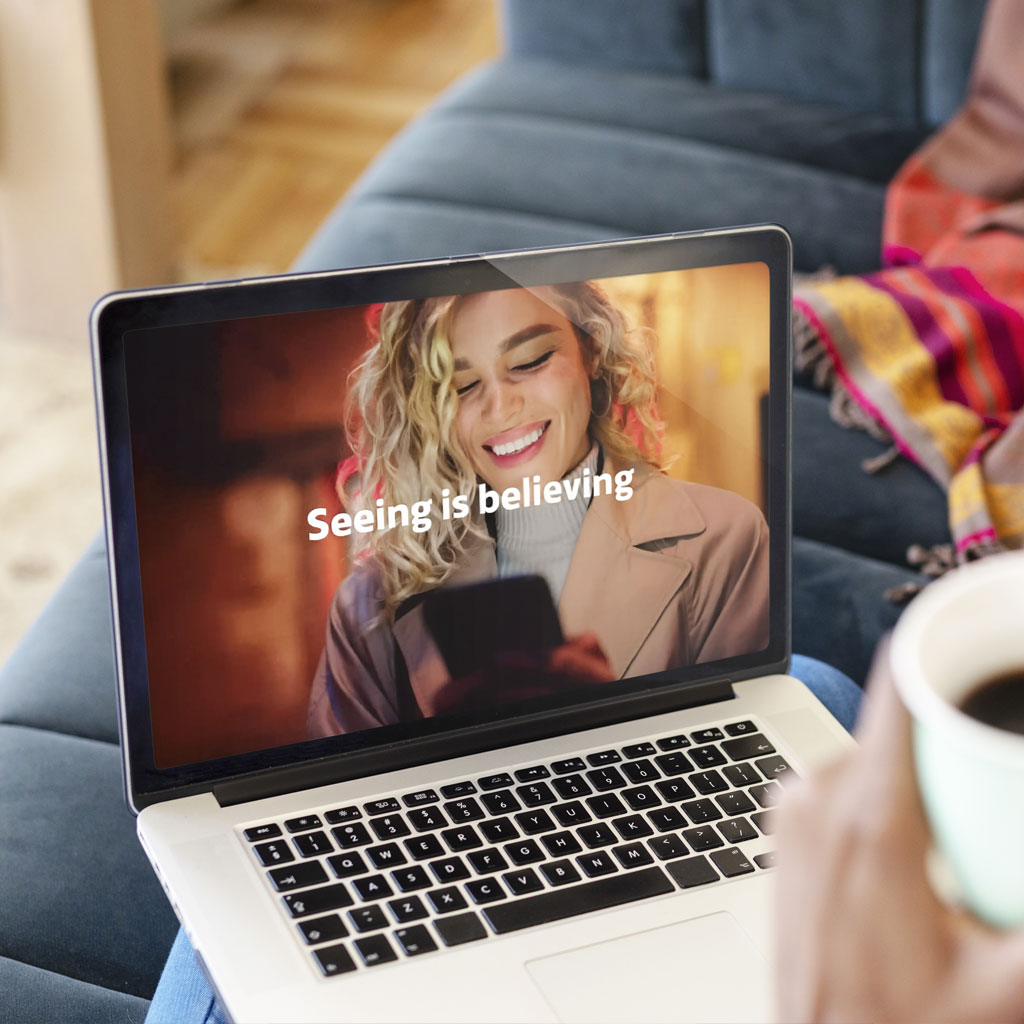 Person browsing a product video on a laptop while relaxing at home, illustrating how rich media enhances the digital shopping experience.