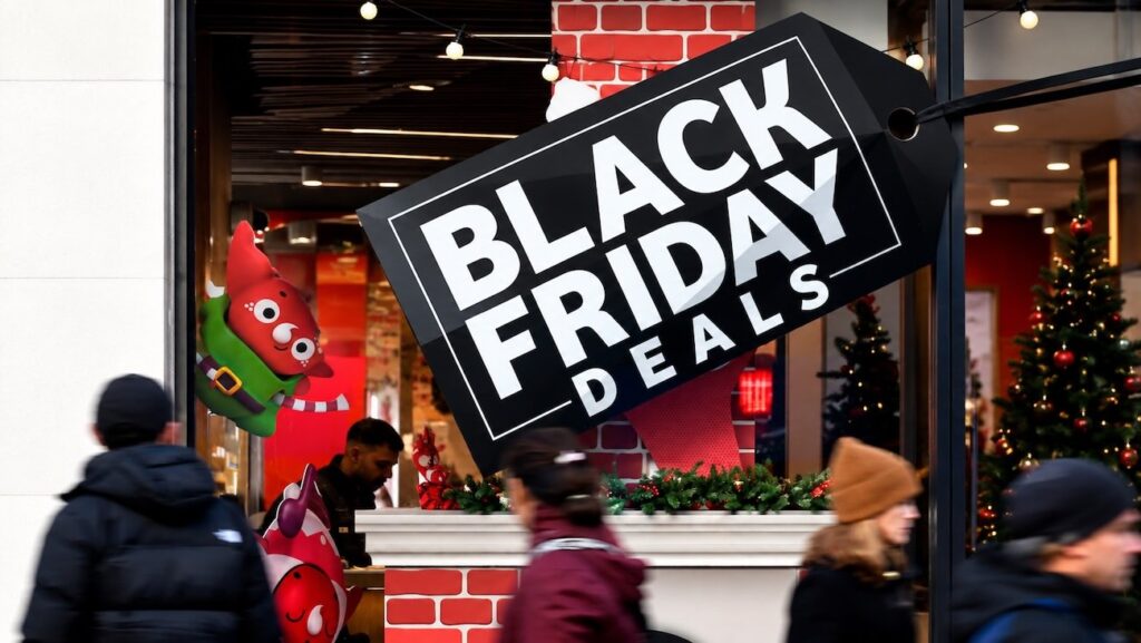 Black Friday deals sign in a retail store window as shoppers pass by during the holiday shopping season.